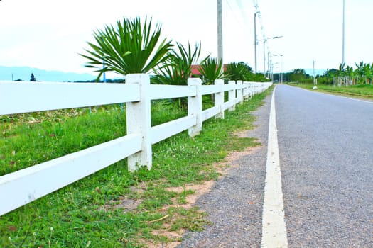 Long  private, country road along a white picket fence