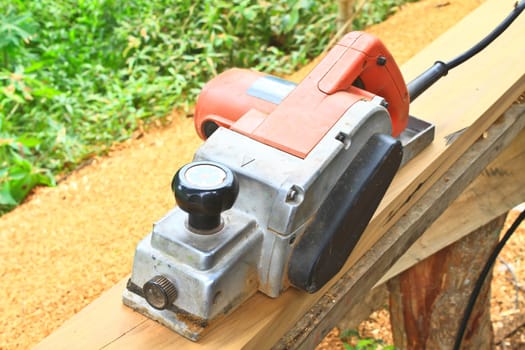 Close up construction worker's hand and power tool while planing a piece of wood trim for a project