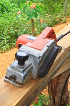 Close up construction worker's hand and power tool while planing a piece of wood trim for a project