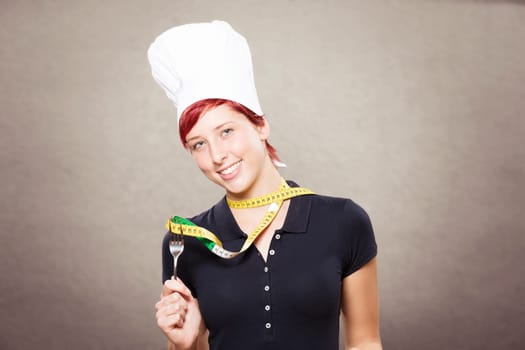 Happy cook holds tape measure with a fork