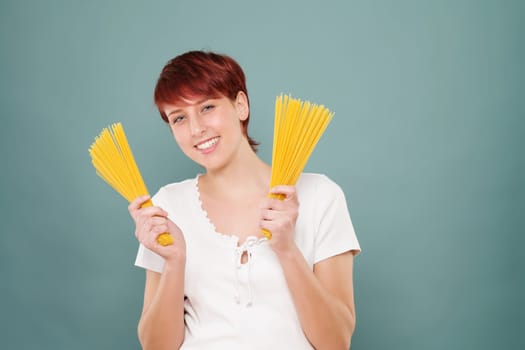Young laughing red-haired woman holds spaghetti