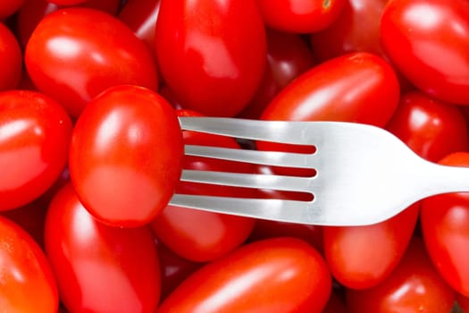 Metal fork and pile of small red tomatoes