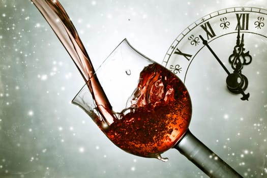 Red wine against fireworks, holiday lights and clock close to midnight