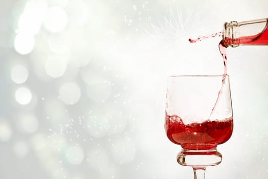 Pouring red wine against festive holiday lights