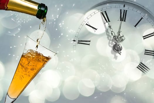 Pouring champagne against holiday lights and clock close to midnight