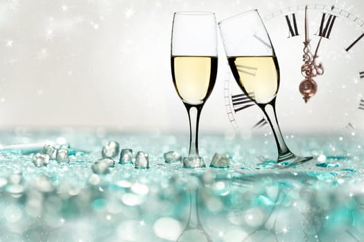 Glasses with champagne against holiday lights and clock close to midnight