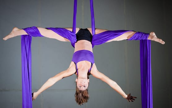 Beautiful woman gymnast performing aerial exercises