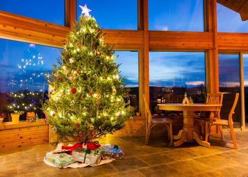 Beautiful decorated Christmas tree in a modern home with large windows