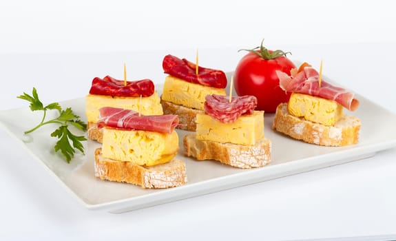 thin slices of Iberian sausage omelette with bread on white base