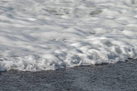 Foam produced by the wave breaking on the beach