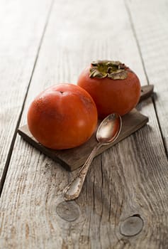 Persimmons - kaki on wooden table close up