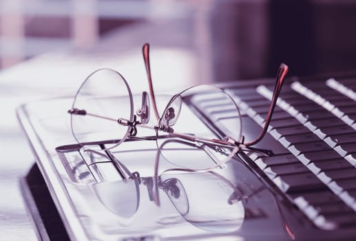 Glasses on the laptop keyboard. Concept search and research on Internet websites.