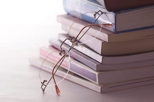 Glasses resting on books. Concept of reading, teacher and student. The image represents the teaching and wisdom.