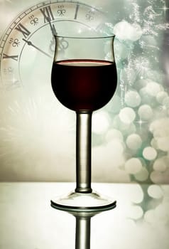 Red wine against fireworks, holiday lights and clock close to midnight