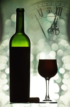 Red wine against holiday lights and clock close to midnight