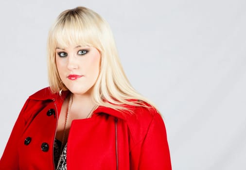 Portrait of a beautiful young woman in red coat against white background
