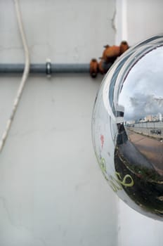 View of cityscape reflected on convex parking mirror. Abstract background.
