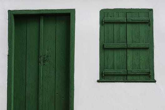 Wooden door and window shutter. Old house white wall background texture.
