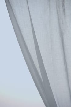 Window curtain against the sky. Folded textile abstract background.