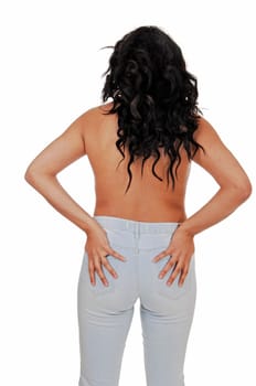 A topless young woman standing from the back for white background in jeans.with her long black curly hair..