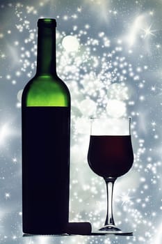 Glass and bottle of red wine against holiday lights