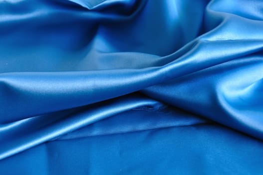 Blue fabric texture. Folded silk textile abstract background.