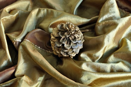 Golden cone on silk texture. Christmas decoration seasonal background.