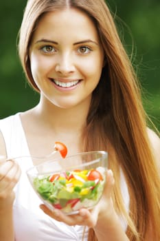 Close-up of happy beautiful young woman eating vegetable salad