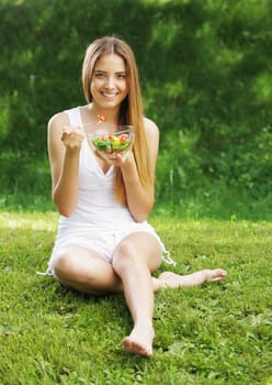 Portrait of happy beautiful young woman eating vegetable salad