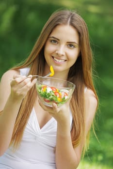 Portrait of happy beautiful young woman eating vegetable salad