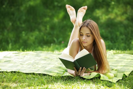 Closeup of a beautiful young woman reading book at park