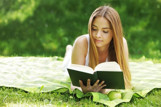 beautiful young woman reading book at park