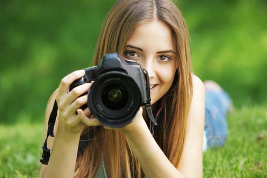 Portrait of beautiful smiling blonde girl , making photos at summer green park.