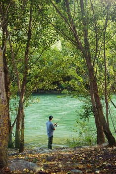 mid adult man on holidays on river, relaxing and fishing trout