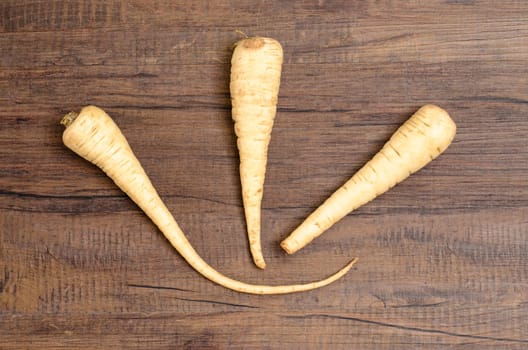 Three parsnips on a brown wood