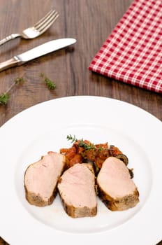 Pork tenderloin fried with tomatoes and olives in portrait format