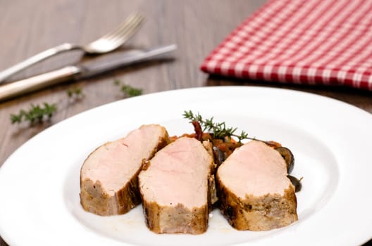 Three slices of roasted pork tenderloin on one plate