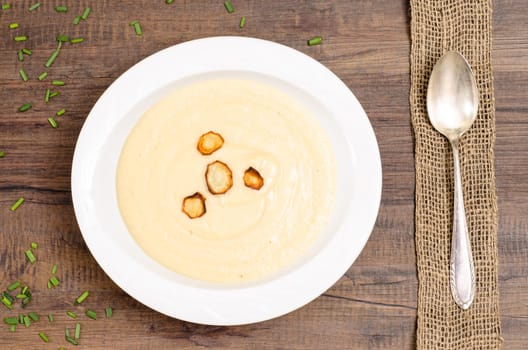 Plate of parsnip soup on a brown wooden table