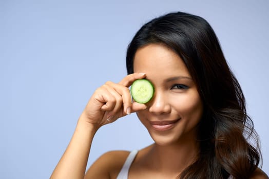 Young people and body care with portrait of happy asian girl smiling with cucumber for skin treatment