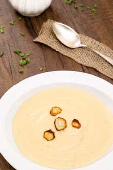 Parsnip cream soup with roasted parsnips on a white plate