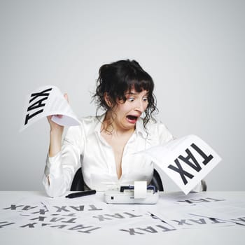 Very surprised  woman at her desk looking at terrible tax bills
