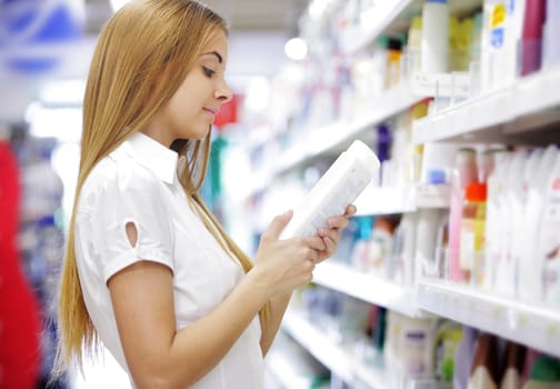 woman in a supermarket reading the label behind a package
