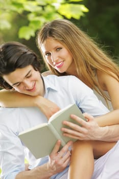 a young couple read a book together in the park. close up.