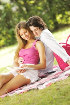 a young couple read a book together in the park
