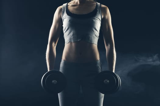 Fitness woman with weights on dark background