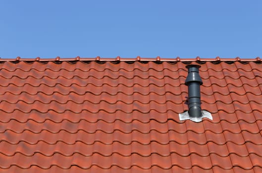 Red roof with chimney against a blue sky