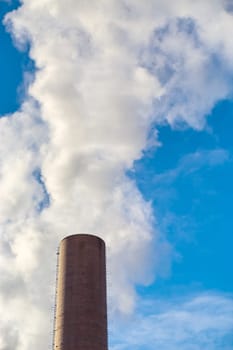 Chimney with smoke against a blue sky