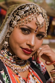 Portrait of a beautiful Kalbelia dancer in ornate black costume trimmed with beads and sequins at the Sarujkund Fair near Delhi in India.
