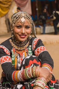 Beautiful Kalbelia dancer in ornate black costume trimmed with beads and sequins at the Sarujkund Fair near Delhi in India.