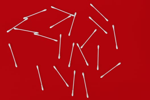 Ear buds white cotton swabs on red background.